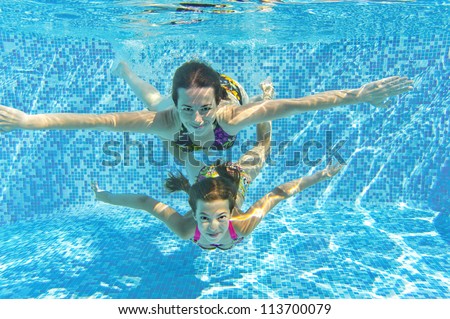 Happy smiling family underwater in swimming pool. Mother and child swim and having fun. Kids sport on family summer vacation. Active healthy holiday