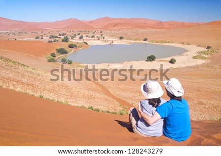 Travellers in Africa, couple on romantic vacation in Namibia, looking at beautiful Namib desert landscape