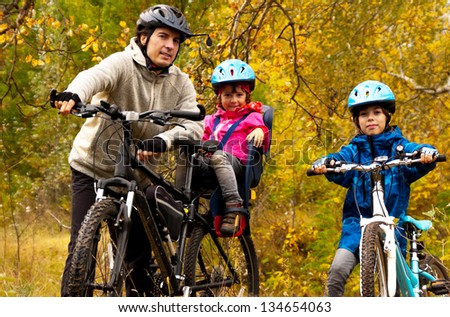 Family cycling outdoors, golden autumn in park, farher and kids on bikes, family sport