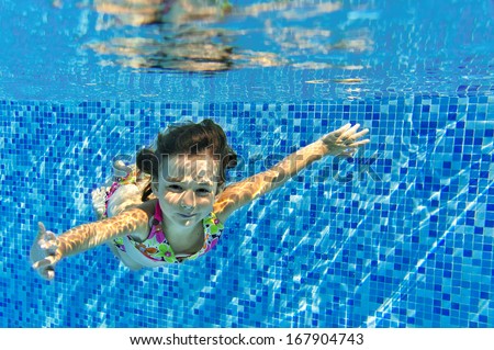 Happy active child swims underwater in pool, beautiful healthy girl swimming and having fun on family summer vacation, kids sport concept