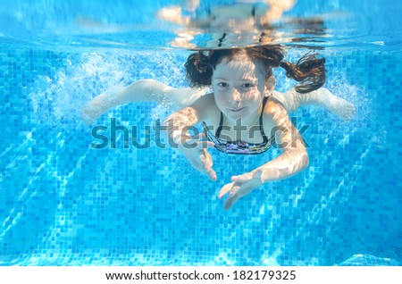Happy active girl swims underwater in pool, beautiful healthy child swimming and having fun on family summer vacation, kids sport concept