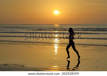 Silhouette of woman jogger running on sunset beach, fitness and healthy life concept