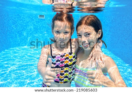 Happy active kids swim in pool and play underwater, girls diving and having fun, children on summer  vacation, sport concept