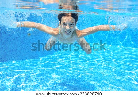 Happy active underwater child swims in pool, beautiful healthy girl swimming and having fun on family summer vacation, kids sport