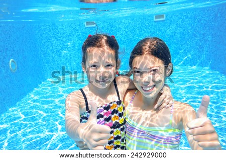 Kids swim in pool underwater, girls swimming, playing and having fun, children water sport
