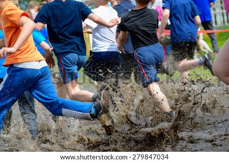 Kids running trail race, legs in mud and water