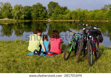 Family bike ride outdoors, active parents and kid cycling and relaxing near beautiful river