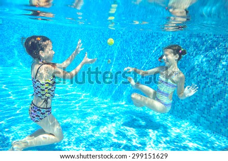 Happy children swim in pool underwater, girls swimming, playing and having fun, kids water sport