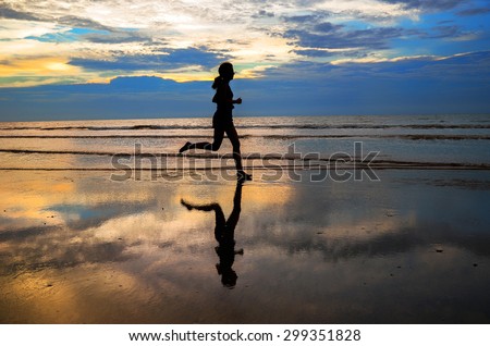 Silhouette of woman jogger running on sunset beach with reflection, fitness and healthy life concept