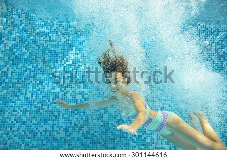Happy girl jumps and swims in pool underwater, happy active child has fun in water, kid sport on family vacation