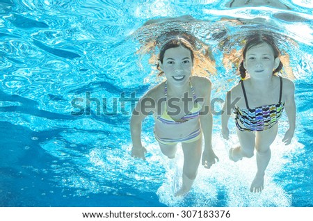 Children swim in pool underwater, happy active girls have fun in water, kids sport on family vacation