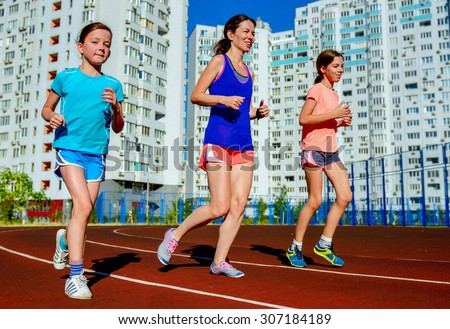 Family sport, happy active mother and kids jogging on track, running and working out on stadium in modern city