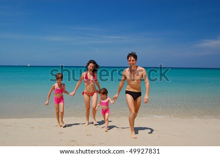 Family of four in swimming suits on tropical beach. Family vacation