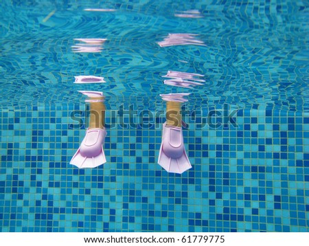 Underwater kid's legs in fins in swimming pool