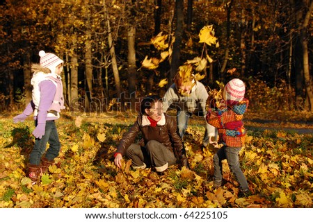 Happy family with two kids throwing leaves in autumn park