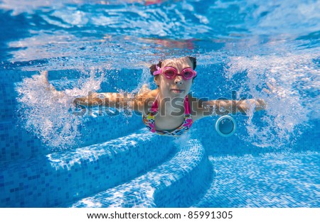 Happy kid swimming underwater in pool. Active girl swims and having fun. Child sport on summer vacation