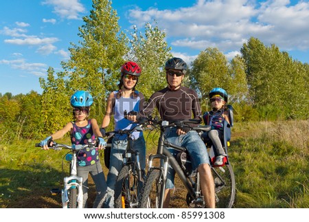 Happy family cycling outdoors. Parents with two kids on bikes