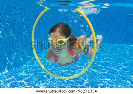 Happy active child swims underwater in swimming pool. Smiling beautiful girl in pool. Kids sport