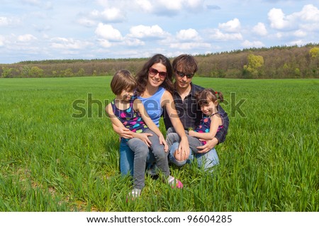 Happy family outdoors having fun. Active parent with their kids on green field. Father, mother and children on family vacation.