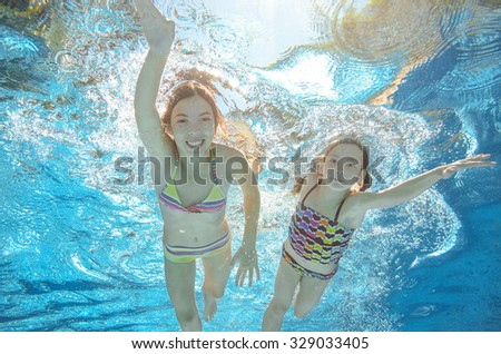Children swim in pool or sea underwater, happy active girls have fun in water, kids sport on family vacation