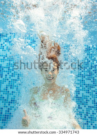 Girl jumps and swims in pool underwater, happy active child has fun in water, kid sport on family vacation