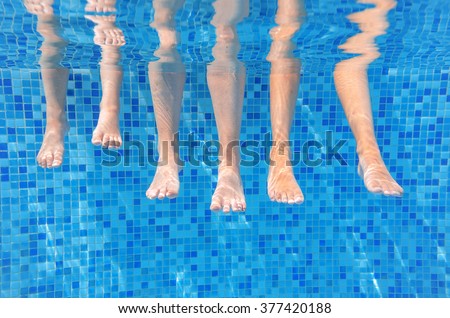 Funny underwater family legs in swimming pool, under water view of mother and kids, vacation and sport concept