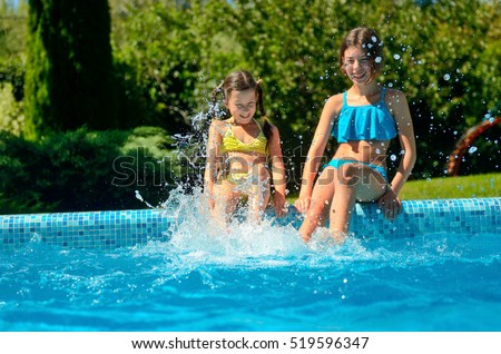 Kids in swimming pool have fun, girls splash in water, happy active children on family vacation