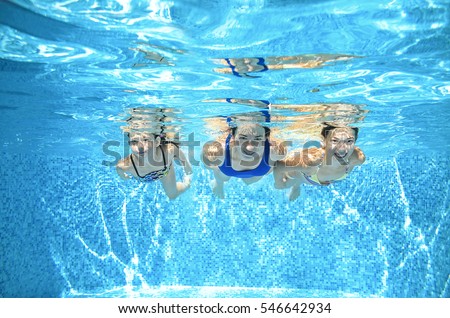 Family swims in pool under water, happy active mother and children have fun, fitness and sport with kids on summer vacation