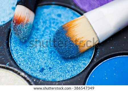 Brushes for make-up on the eye shadow palettes. Texture of crumbly  blue sparkling shadows.