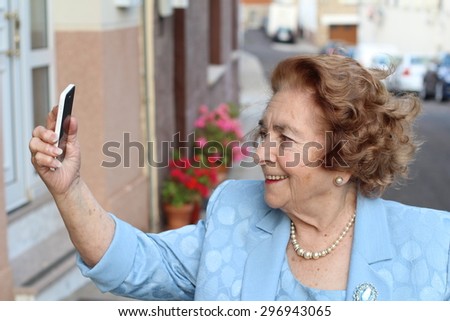 Happy elderly woman reading emails on smart phone at home