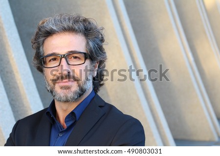 Mature elegant professional with glasses standing outside the office with copy space