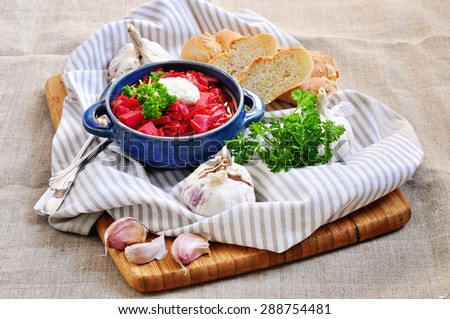 Red beet soup in a bowl with garlic, bread, and parsley. Selective focus