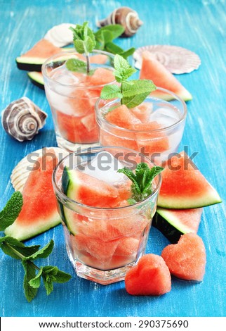Refreshing summer watermelon drink with mint and ice cubes, sea shells, selective focus, toned image.