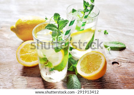 Refreshing iced mint tea with lemon and ice cubes, a drink for hot summer days selective focus, toned image
