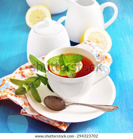 Tea with lemon and mint on a blue background, table setting for tea time, selective focus, toned image