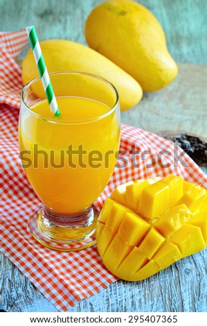 Fresh tropical mango juice and  mango fruits on wooden background. Selective focus.