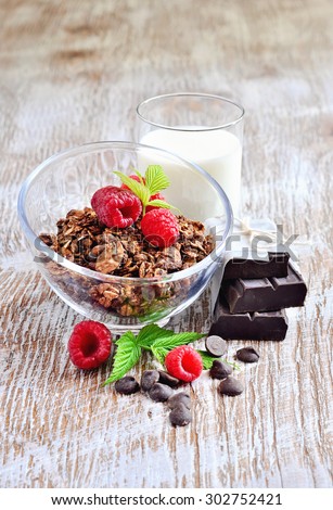 Chocolate granola, milk, and raspberries, muesli for healthy breakfast, morning meal, selective focus