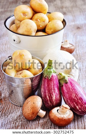 Fresh organic vegetables, potatoes, onion, egg plant, and mushrooms, seasonal harvest, rustic background, selective focus, toned image