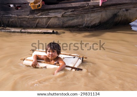 SIEM REAP, CAMBODIA - MAY 1: A 3-year old child learns swimming via a handmade buoy and she lives on floating villages around Tonle Sap lake May 1, 2009 in Siem Reap, Cambodia.
