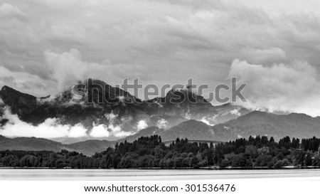 black & white landscape from lake forggen over allgaeu woods to some alp mountains
