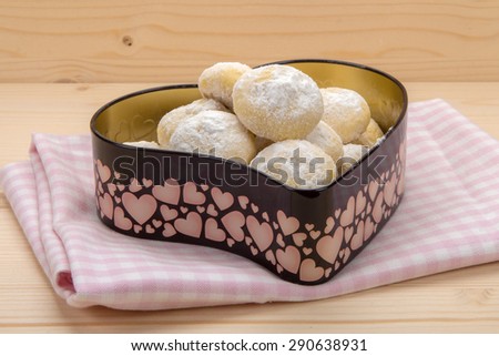 Small cookies in powdered sugar in a tin box in heart shape