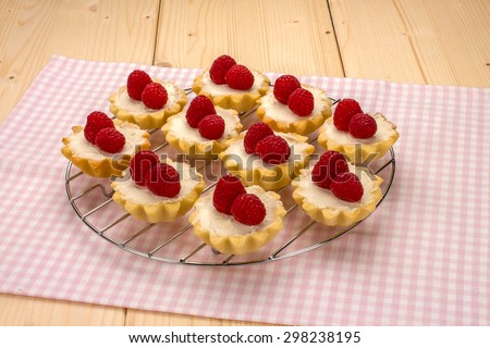 Homemade small cakes with cream cheese and fresh raspberries on a cotton napkin with a checkered pattern