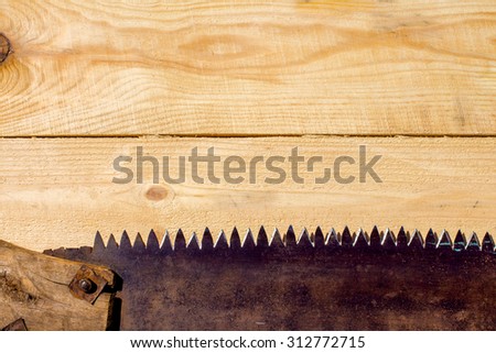 Rusty saw with a wooden handle on a wooden table from light boards