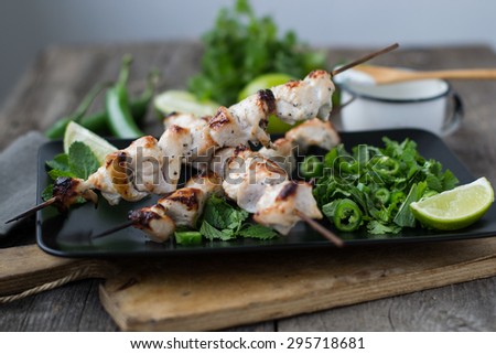 Skewers of chicken with salsa with lime, mint, cilantro and hot peppers served with yogurt sauce on a wooden background