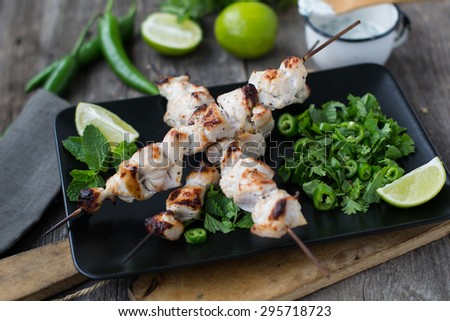 Skewers of  chicken with salsa with lime, mint, cilantro and hot peppers served with yogurt sauce on a wooden background