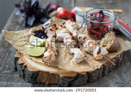 Skewers of chicken with salsa of basil, tomatoes and red onions served with yogurt sauce on a wooden background