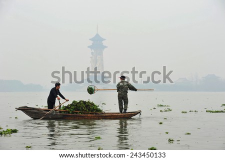 TAIZHOU, CHINA - NOVEMBER 21, 2014: Unidentified Chinese women scoop water hyacinth (weed) from the waters of the Qinhu National Wetland Park outside of TaiZhou China.