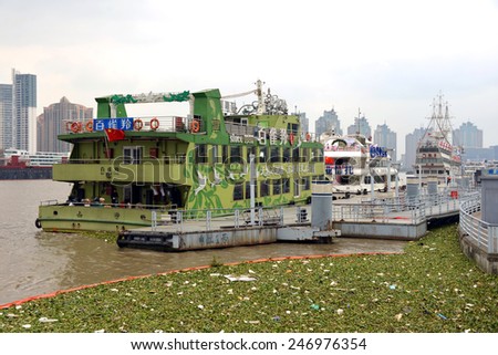 SHANGHAI, CHINA - NOV 9, 2014: Water Hyacinth corralled in Huangpu River of Shanghai and docked tour boats.  It is an invasive species and the problem has been compounded by the warm Autumn weather.