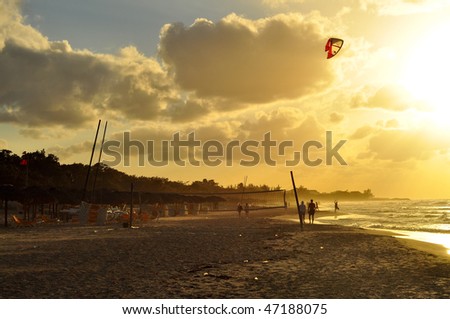 People enjoy beautiful beach in Varadero, Cuba at sundown bathed in glorious golden light.  Kite-boarder comes in from the ocean