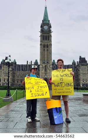 OTTAWA, CANADA - JUNE 6:  Two Canadians hold signs at demonstration on Parliament Hill imploring British Petroleum to do more to fix their oil spill disaster.  Ottawa, Ontario June 6, 2010.